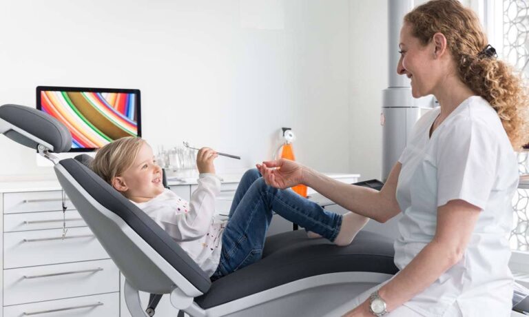 A smiling child sitting comfortably on a dental chair during a friendly dental checkup with a dentist in a modern clinic